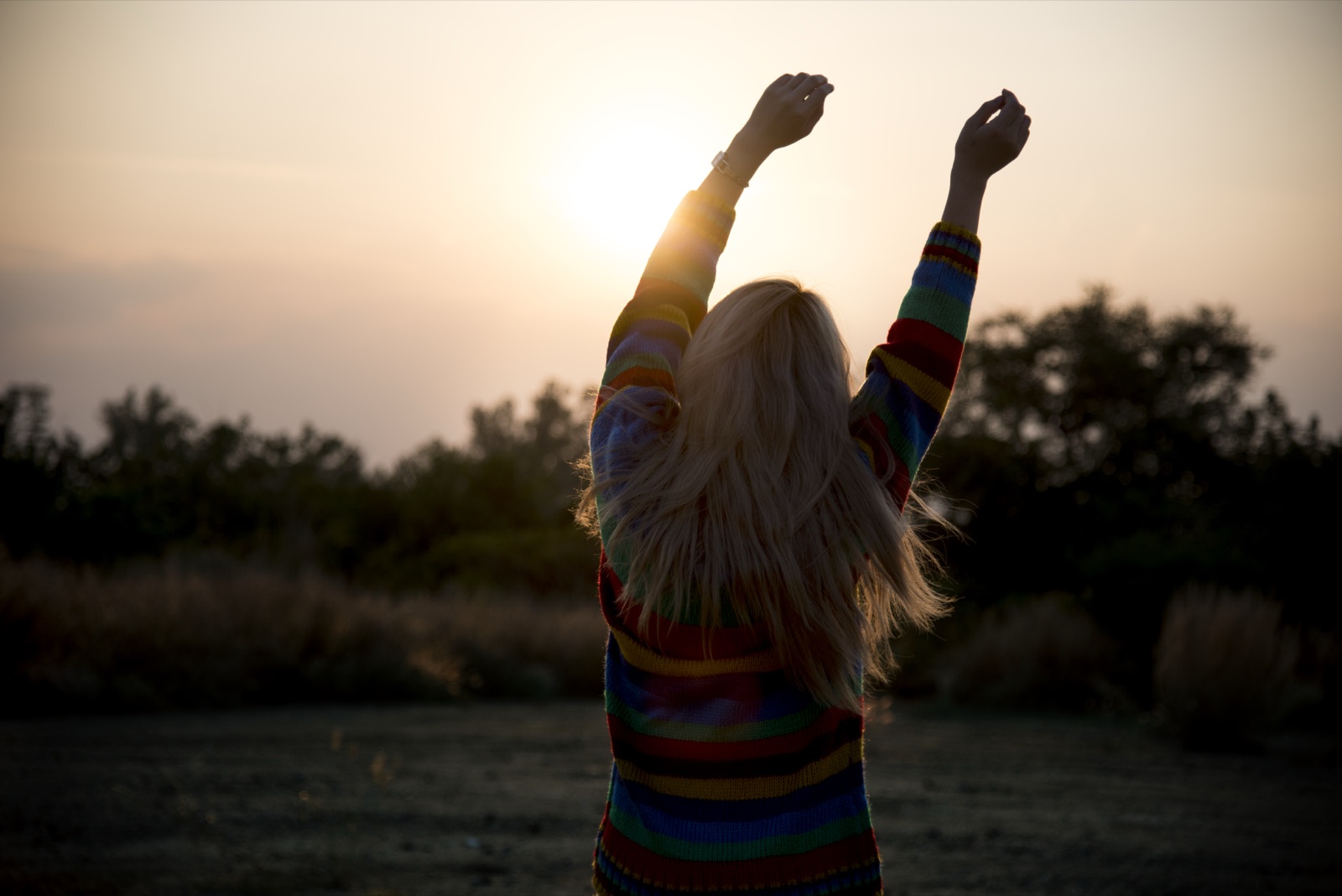 A woman stretching her arms toward the morning sun