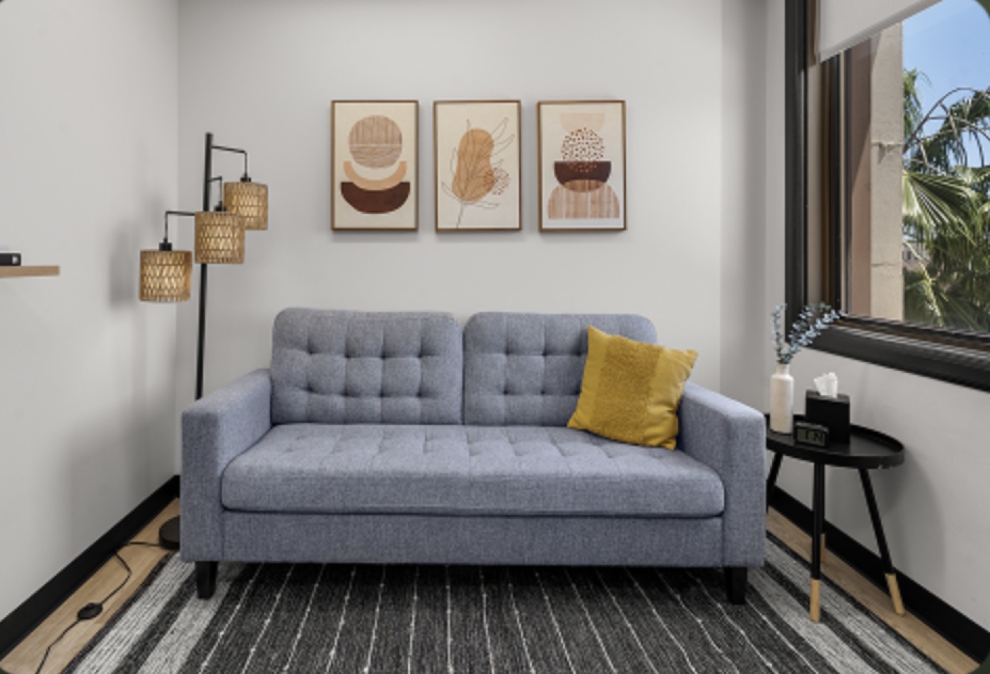 Therapy office with a soft gray sofa, framed art, and warm natural light